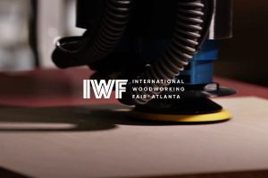 Close-up of a polishing tool on a wooden surface with the IWFF International Woodworking Fair Atlanta logo overlaid