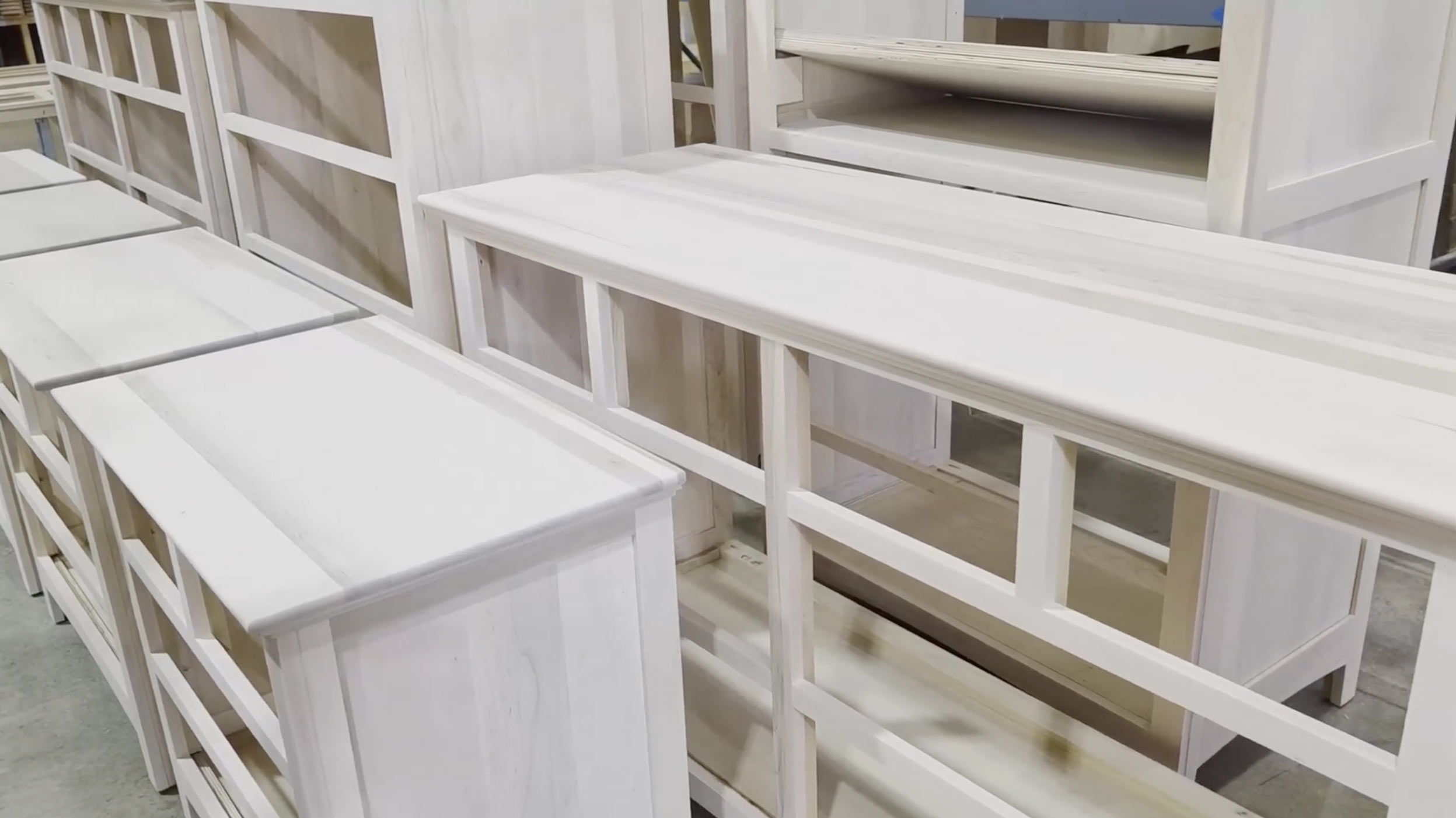 Row of white wooden display shelves arranged in a workshop or warehouse setting.