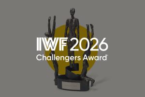 IWF 2026 Challengers Award trophy—a dark bronze sculpture with multiple figures, set against a yellow circle backdrop.
