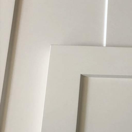 Close-up of a white door frame with layered decorative molding and panels.